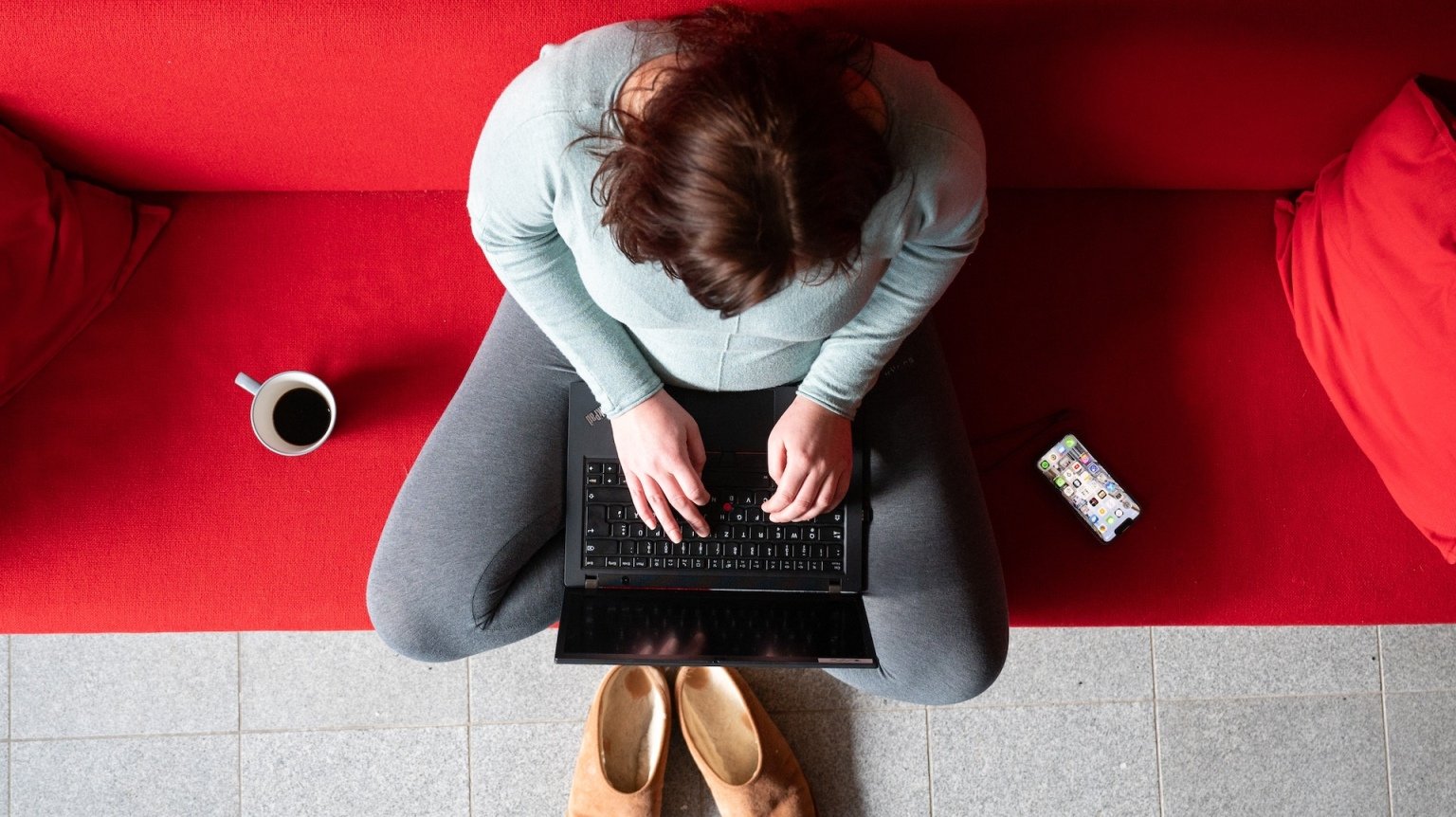 A woman works from home on her couch.