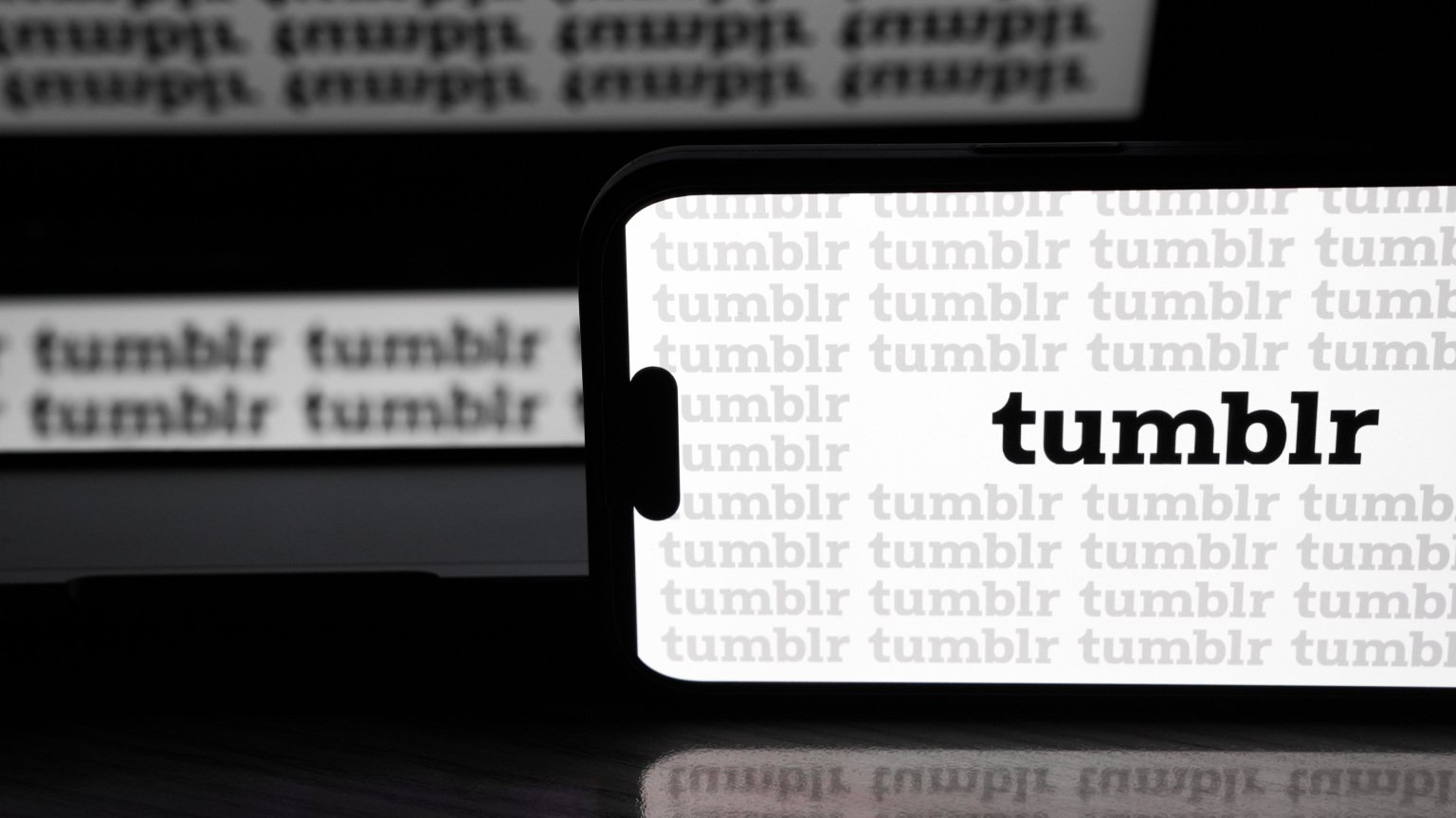 the tumblr logo all over a phone and screen behind the phone