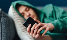 Teen boy wearing a hoodie looks at his phone.