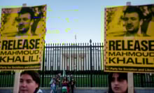 Protesters hold signs that read "release Mahmoud khalil" while standing in front of the White House fence.