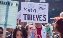 A protester holds a 'Meta book thieves' placard in King's Cross during the march to Meta offices