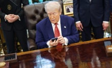 president trump holds an iphone while signing executive order in oval office