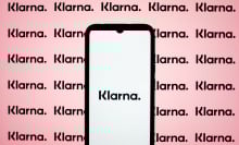 A phone displays the Klarna logo in front of a pink background.