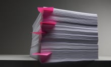 A large stacks of papers with post-it notes in between some of the pages.
