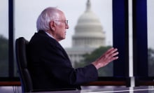 bernie sanders sitting at a desk with the capitol building in the background