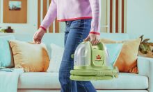 woman carrying bissell little green mini through living room