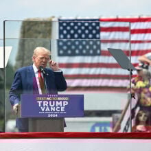 Donald Trump behind bulletproof glass at a campaign rally in 2024