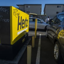 a hertz sign in between two parked cars