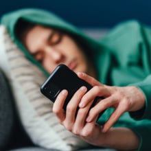 Teen boy wearing a hoodie looks at his phone.