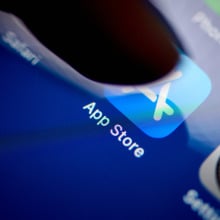 A finger taps on the Apple App Store app on a phone screen.