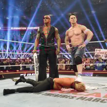 The Rock and John Cena stand over Cody Rhodes at WWE Elimination Chamber