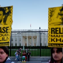 Protesters hold signs that read "release Mahmoud khalil" while standing in front of the White House fence.