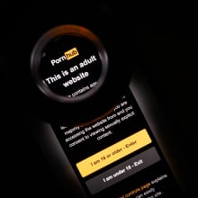 In this photo illustration, the age-restriction warning screen of the website PornHub is displayed on a digital screen