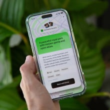 a hand holding a phone with the happn app open, with the app recommending 'a peaceful royal park with hidden gems and open skies'