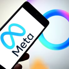 A Meta logo is seen displayed on a smartphone with a Meta AI logo in the background.