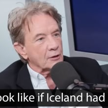 A man sits in a chair in front of a microphone. The quote at the bottom reads, "You look like if Iceland had a face."