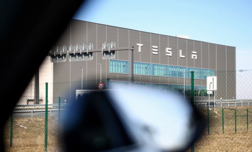 A photo of the outside of a Tesla factory framed through the window of a car. 
