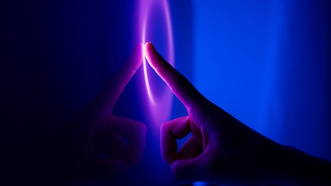 A finger taps a glowing purple and blue touch screens 