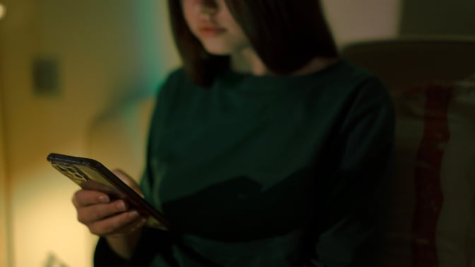 A teen girl looks at her phone. 