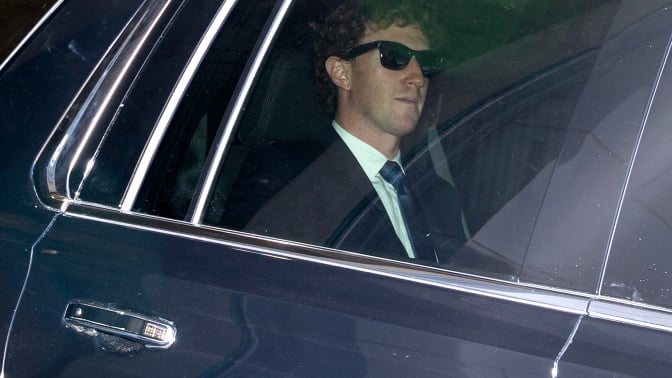 Mark Zuckerberg seen through a car window while wearing black sunglasses and suit 