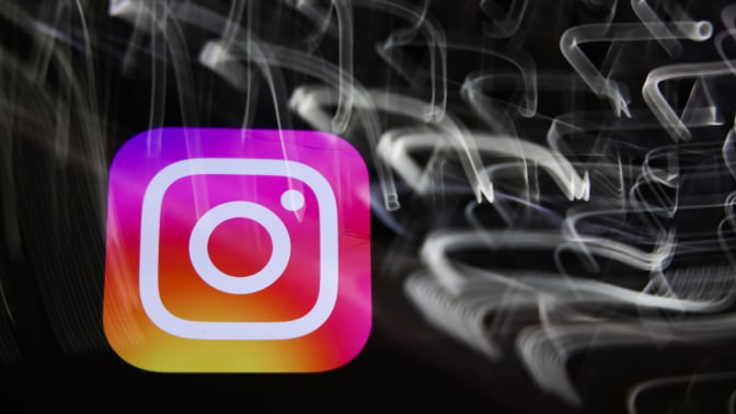 The Instagram logo amid a swirl of blurred white lights on a black background. 