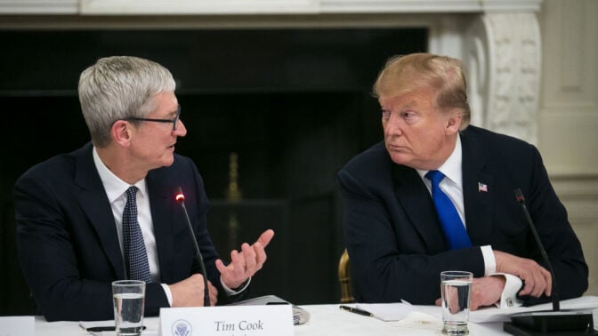 Apple CEO Tim Cook and President Donald Trump, seated at a table, talking