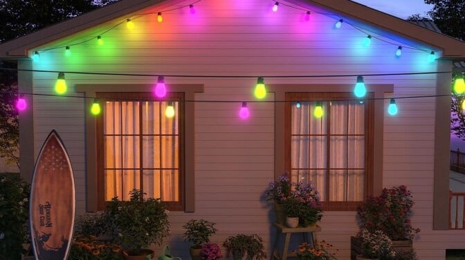 govee outdoor lights on a small home with a surfboard leaning against the house and green grass in the foreground