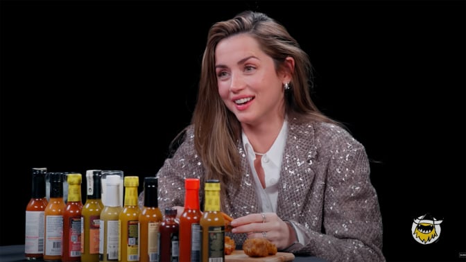 A woman sits at a table covered in sauce in a dark room.