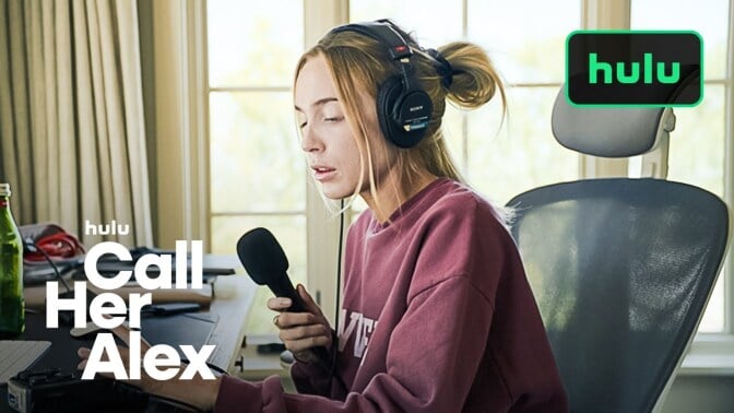 alex cooper sitting a desk with a mic