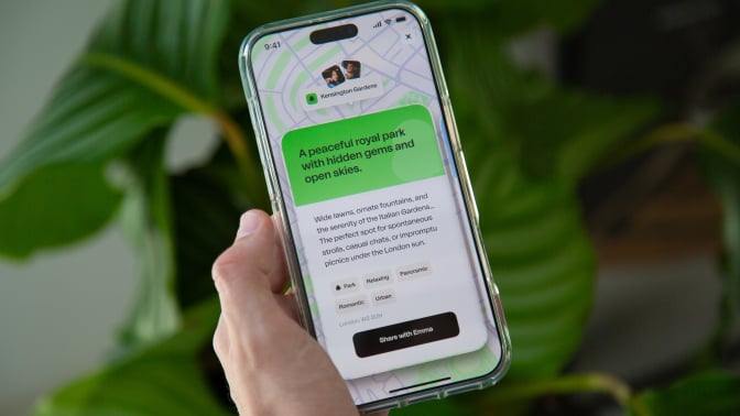 a hand holding a phone with the happn app open, with the app recommending 'a peaceful royal park with hidden gems and open skies'