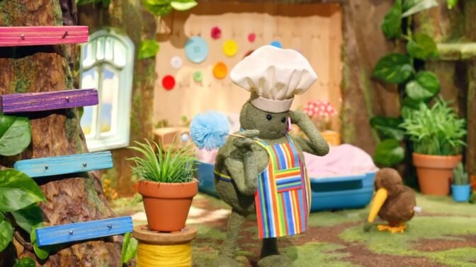 The green tiny chef character wearing a chef's hat and taking a phone call.