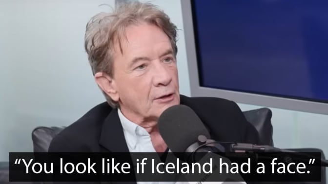 A man sits in a chair in front of a microphone. The quote at the bottom reads, "You look like if Iceland had a face."