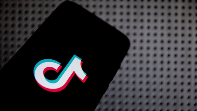 TikTok logo on a phone, against a gray background. 