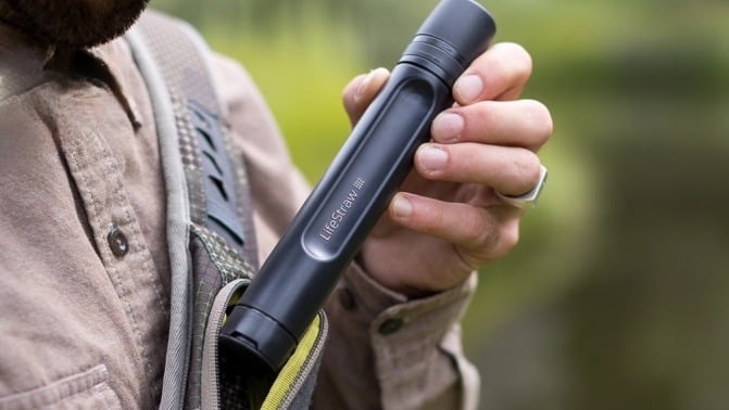 a person holds the LifeStraw water filter while taking it out of a shirt pocket