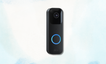 Black Blink video doorbell with a glowing blue ring on a light blue and white background.