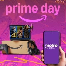 Amazon Prime box and purchases beside hand holding phone with T-Mobile logo on screen, arranged on purple backdrop