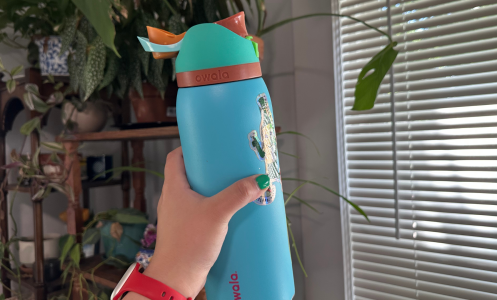 A person's hand holding an Owala FreeSip water bottle