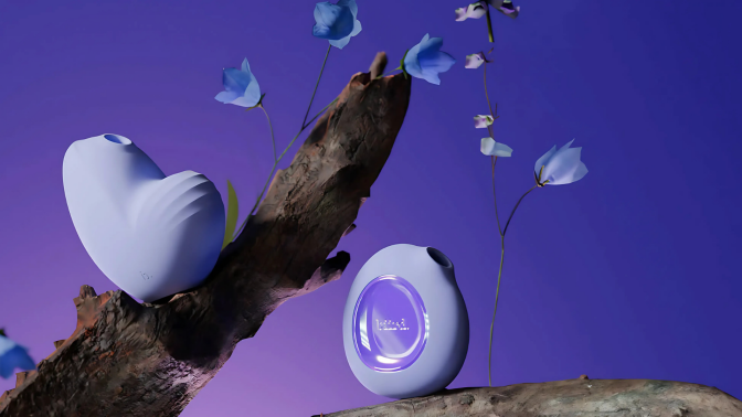 Two periwinkle-colored Biird pleasure objects are artistically arranged on a piece of dark driftwood with delicate light blue flowers against a rich purple background. 