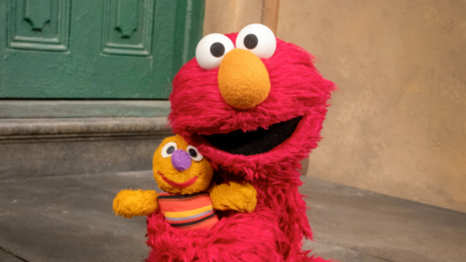 Elmo from 'Sesame Street' hugging a doll.